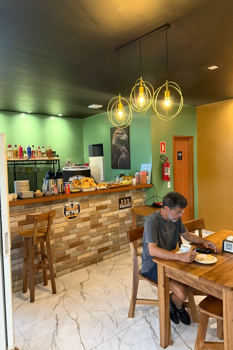 Balcão do bar com luminárias pendentes e mesas de madeira