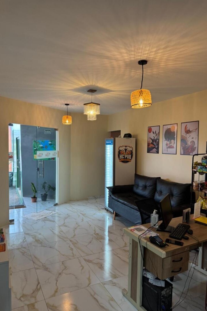 Área interna com sofá, quadros e luminárias pendentes