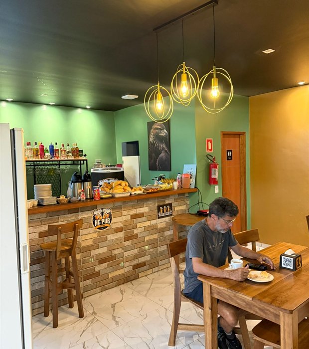 Espaço de café da manhã do Hotel Calleb, com balcão e luminárias