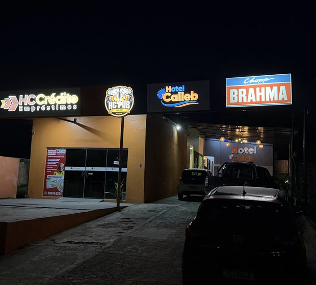 Fachada do Hotel Calleb à noite, com o letreiro iluminado